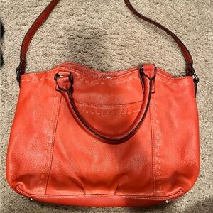 Women’s orange purse with strap and handles. Multiple inside pockets.